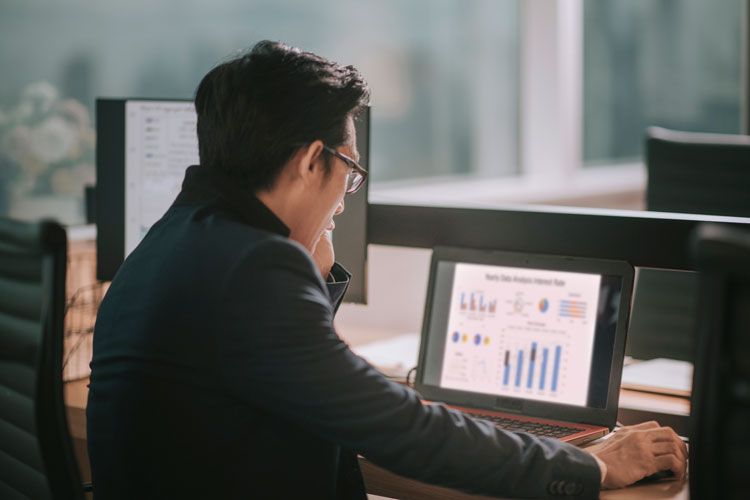 A fleet business owner is reviewing fleet card analytics on his laptop.