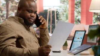 Fleet manager analyzing reports on laptop and phone for fleet card