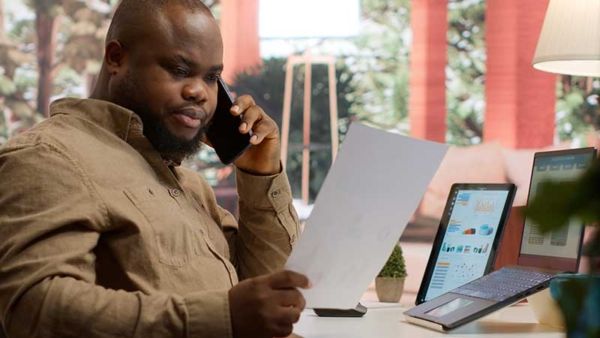 Fleet manager analyzing reports on laptop and phone for fleet card