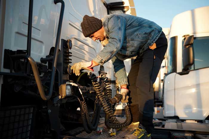A fleet truck driver checks his air brake hoses on his rig.