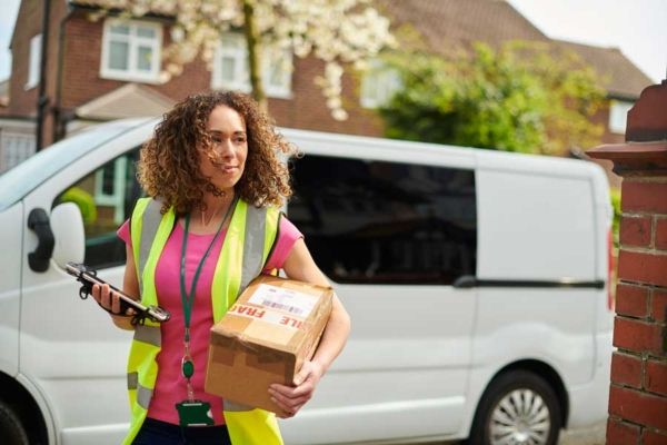 A fleet driver of a van delivers a package on her route.